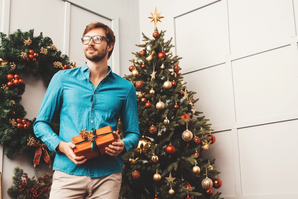 portrait smiling handsome man holding gift sexy bearded male posing near christmas tree with present