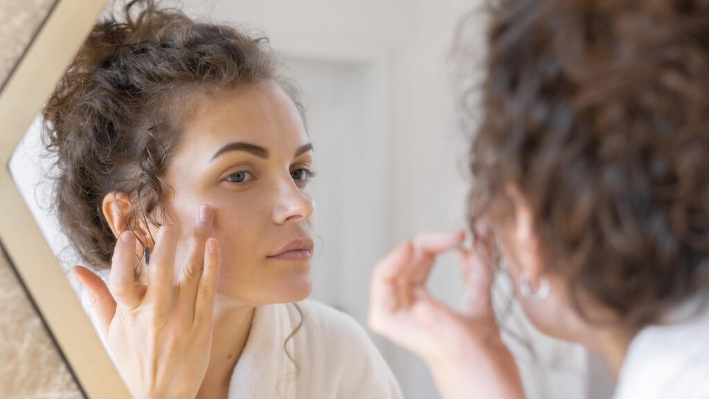 woman looking mirror doing beauty face routine