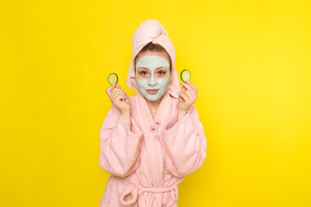 front view young beautiful female pink bathrobe holding cucumber