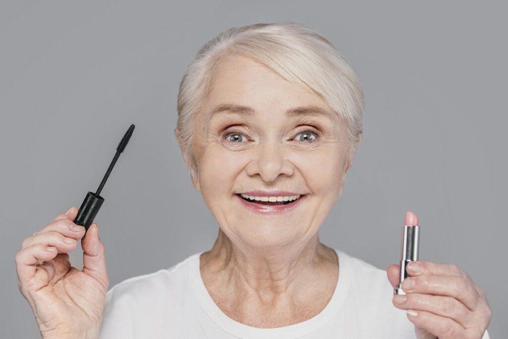 krupnym planom zensina derzit pomadu i tus dla resnic